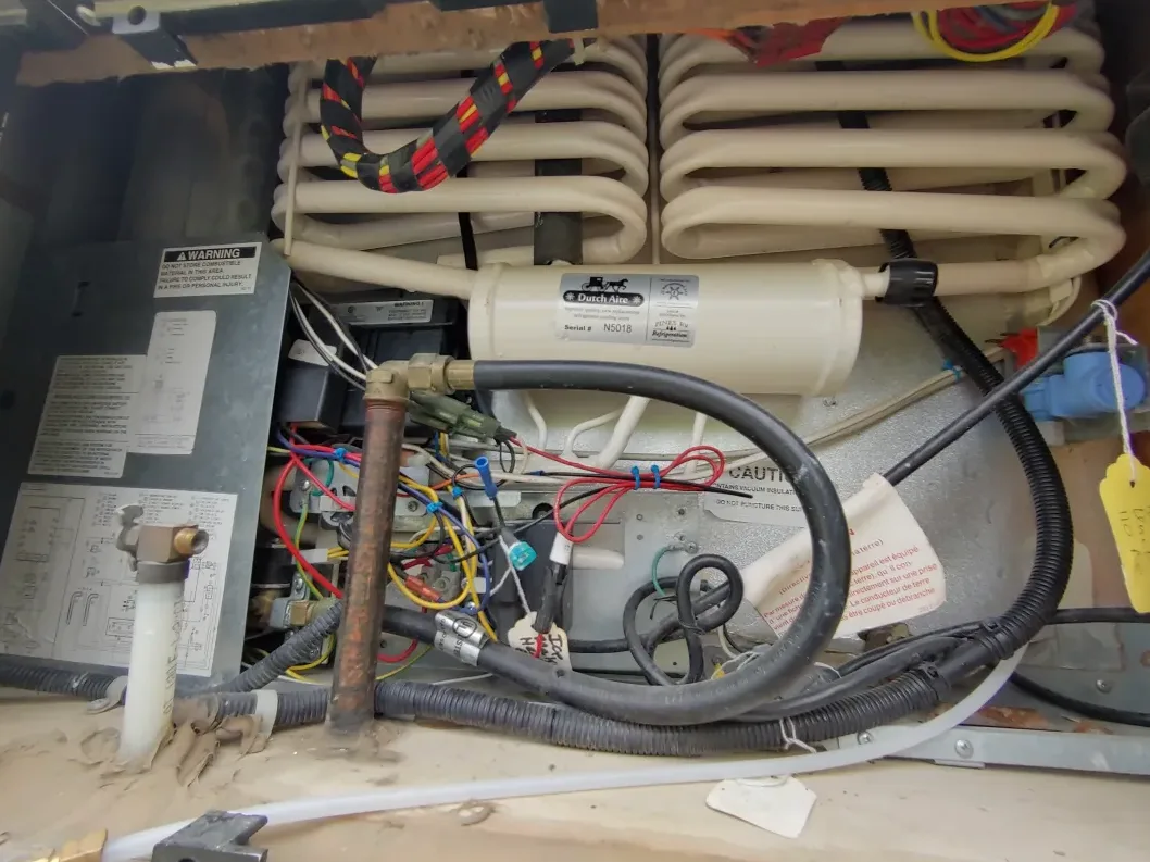 An RV refrigerator cooling unit and gas burner assembly exposed for diagnosis in Fellsmere, Florida